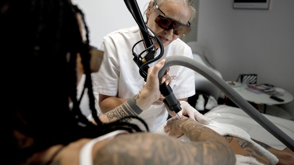 Eine Lasertherapeutin und Heilpraktikerin entfernt mit einer Laserbehandlung ein Tattoo auf der Haut von einer Frau, hier im August 2019 in Berlin.