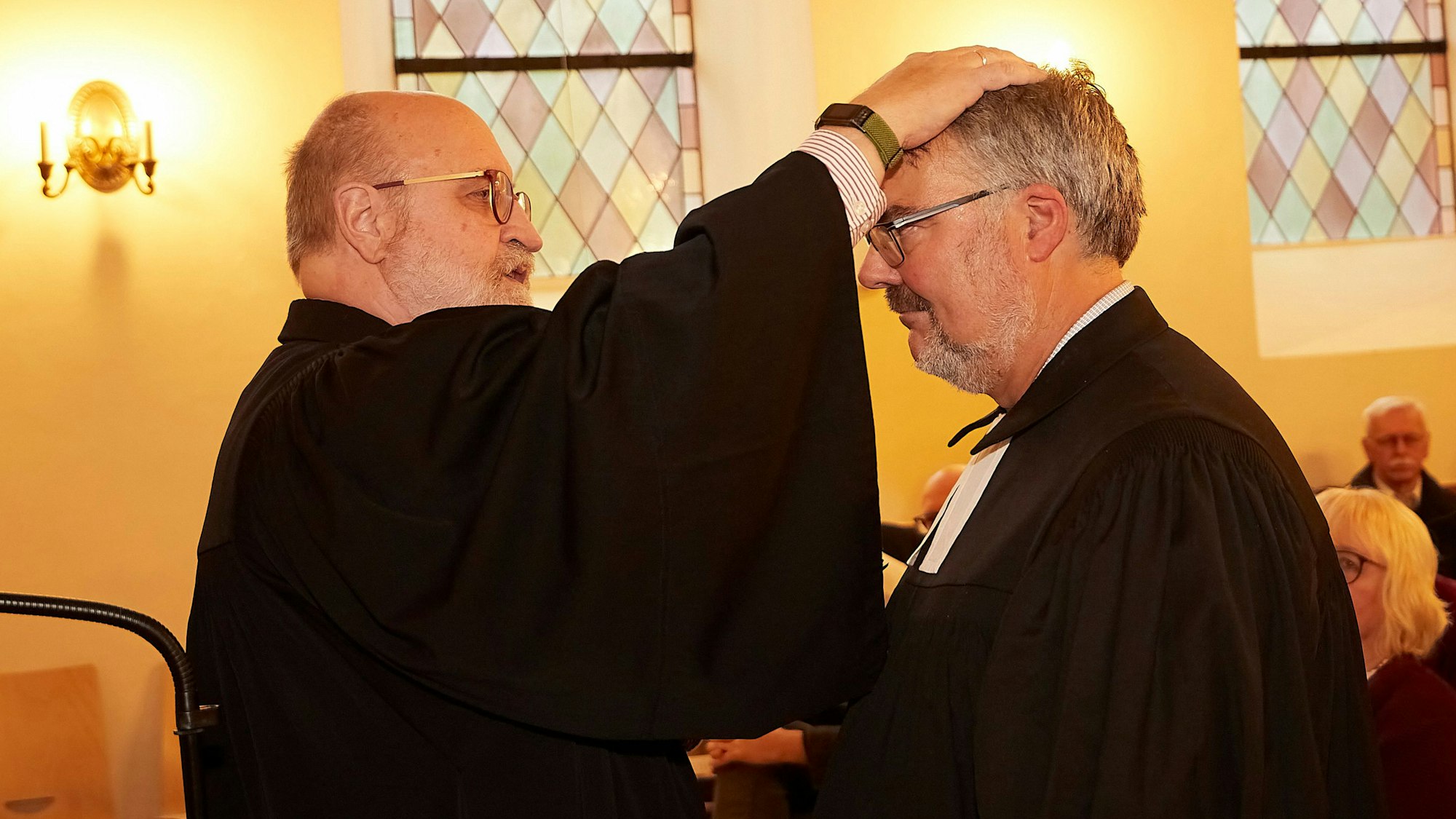 Superindentent Hans-Peter Bruckhoff legt Pfarrer Erik Schumacher zur Segnung die Hand auf den Kopf.
