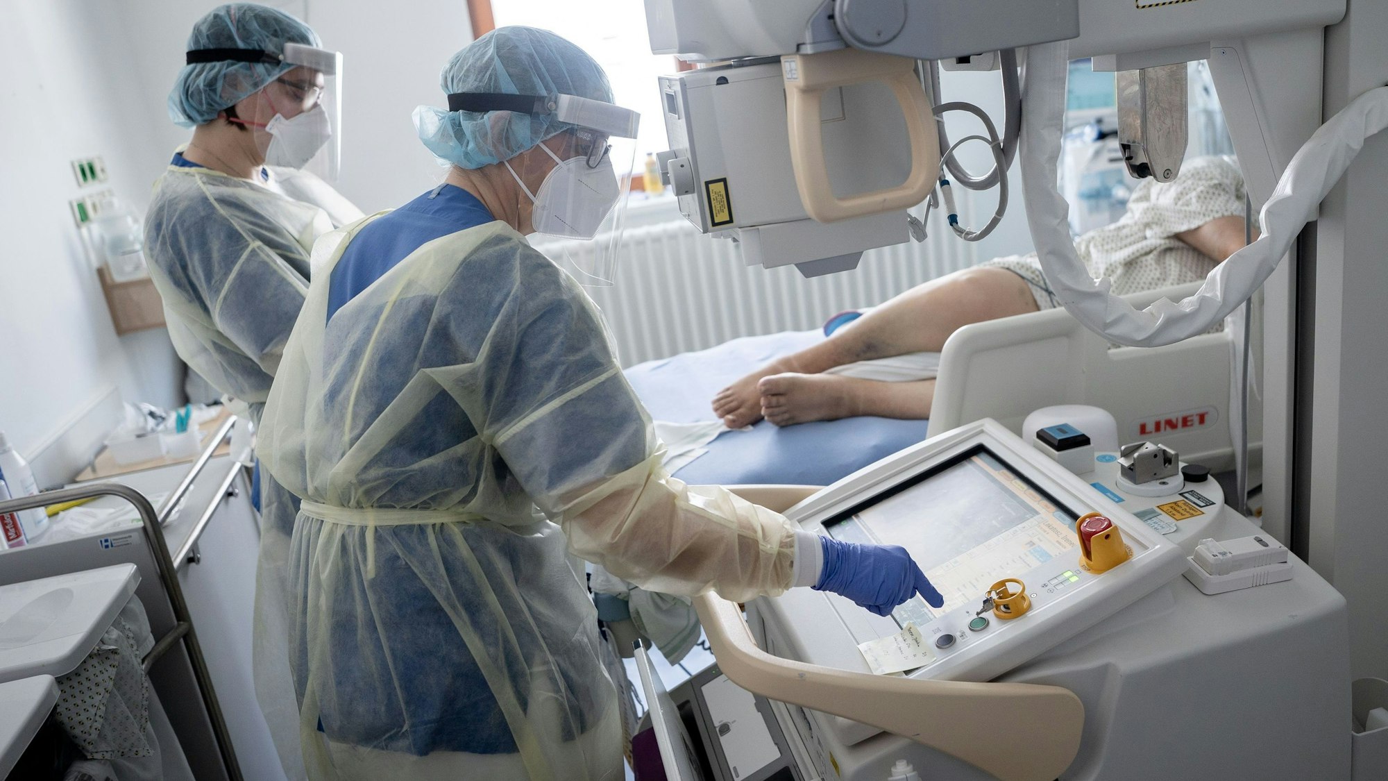 Intensivpflegerin Sandy Plückhahn (l) und Mirjana Suljagic, Röntgen-Assistentin, bereiten auf der Intensivstation des Krankenhauses Bethel Berlin eine an Covid-19 erkrankten Patientin für eine Röntgenaufnahme der Lunge vor.
