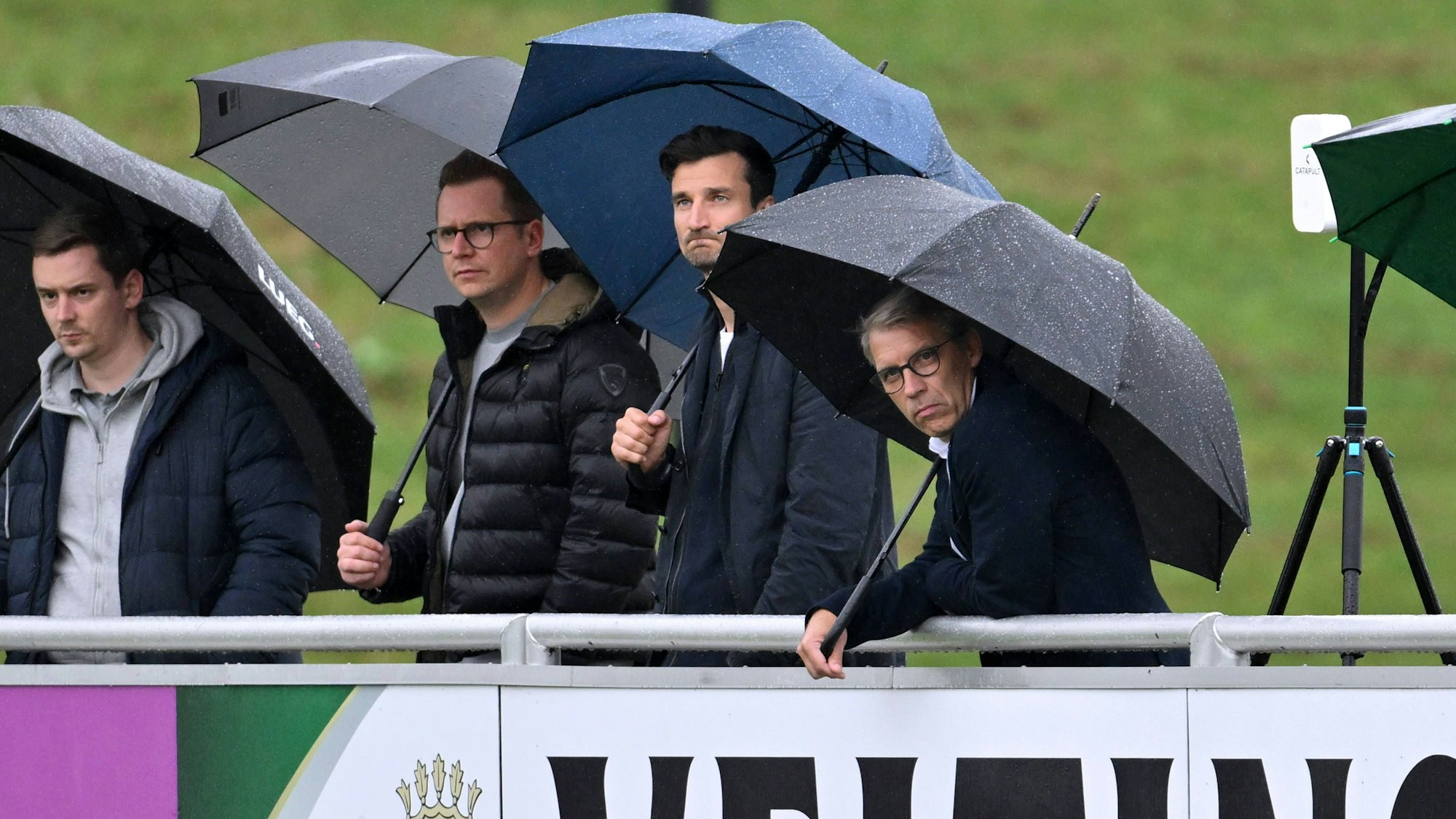 Peter Knäbel steht neben Matthias Tillmann und André Hechelmann im Regen.