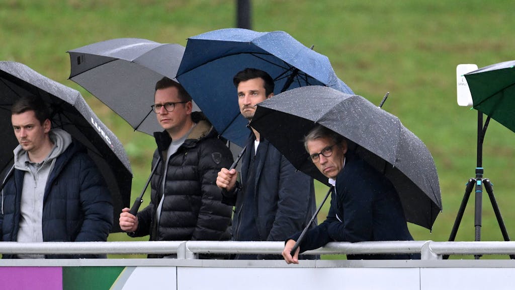 Peter Knäbel steht neben Matthias Tillmann und André Hechelmann im Regen.