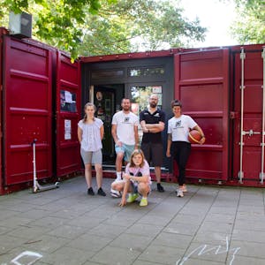 Das Team der„ Grembox“, der Jugendeinrichtung der „Rheinflanke“ in Gremberghoven, steht vor einem ehemaligen Seecontainer, der jetzt eine Jugendeinrichtung ist.