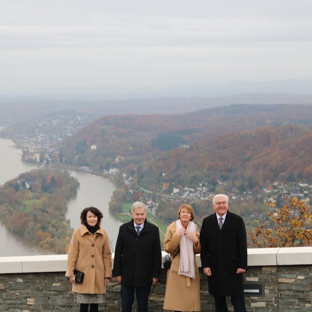 Zwei Frauen und zwei Männer stehen auf dem Drachenfelsplateau, im Hintergrund ist das Rheintal mit der Insel Nonnenwerth zu sehen.