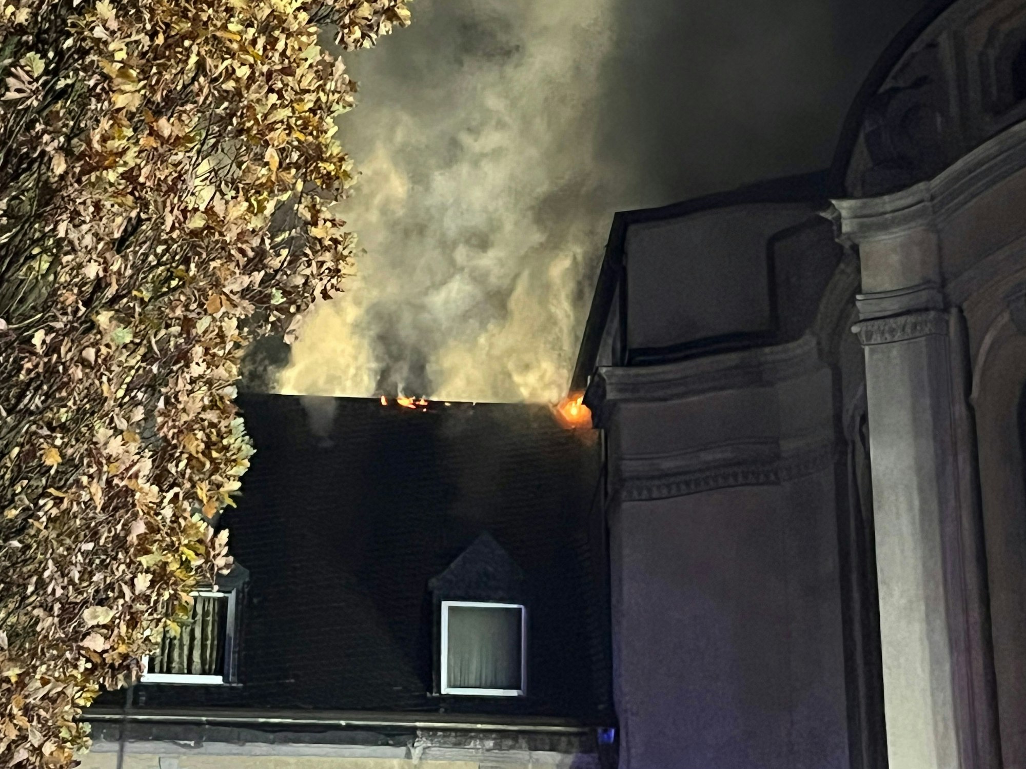 Dichter Rauch und Flammen dringen aus der Dachhaut, unmittelbar neben der historischen Klosterkirche.