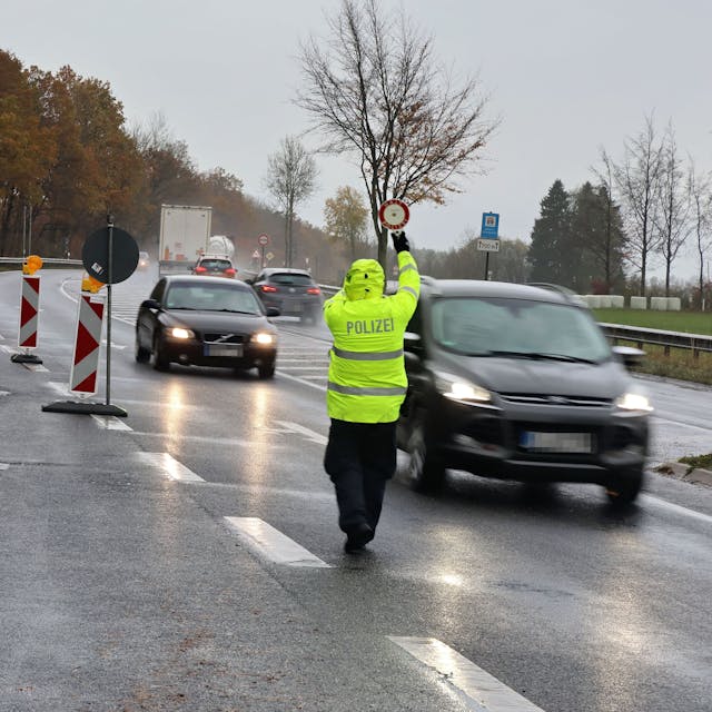Zwei Polizeibeamte winken im strömenden Regen Fahrzeuge aus dem fließendem Verkehr.
