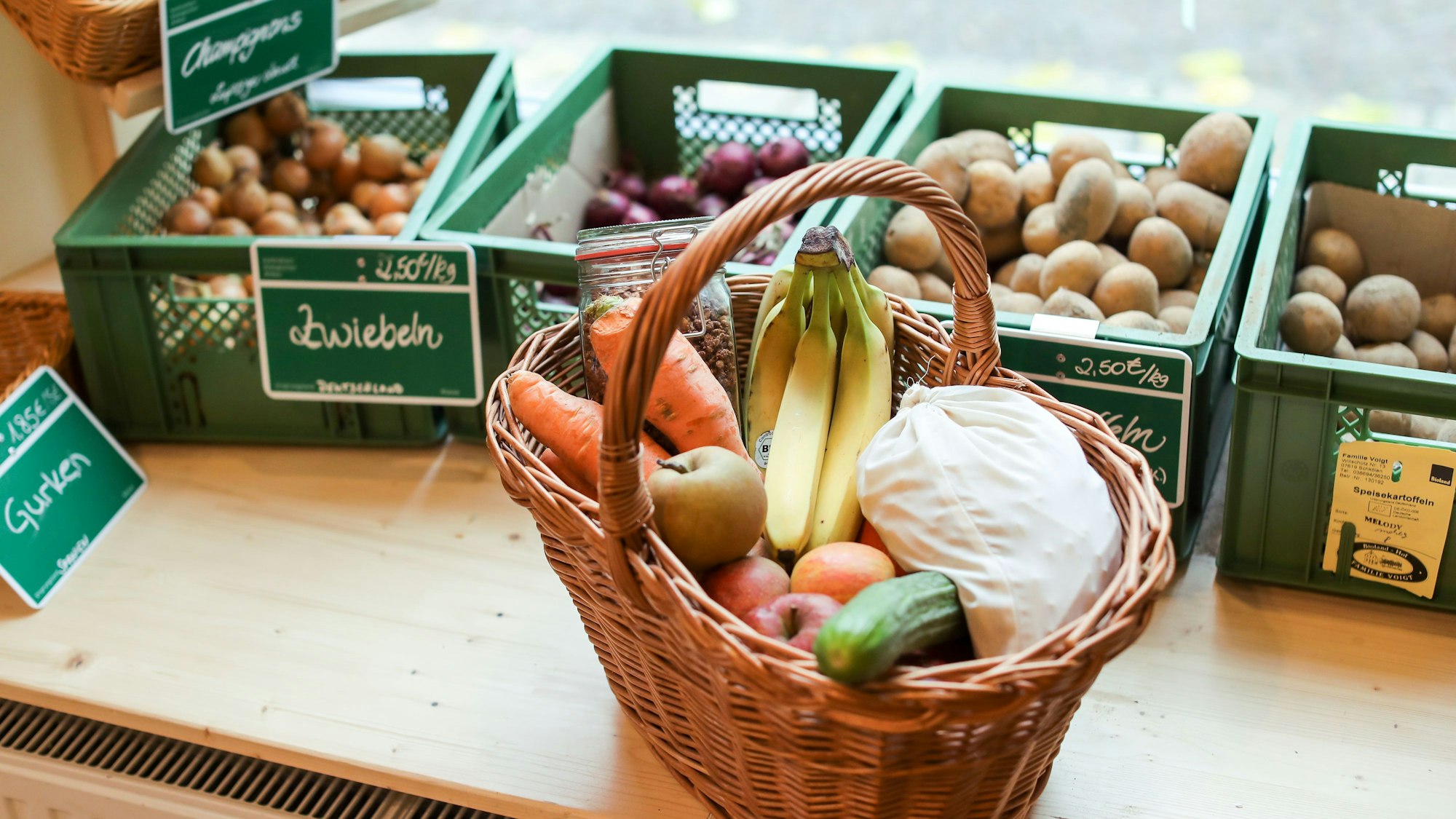 Ein zugeschnürtes Stoffsäckchen mit Nudeln liegt neben Obst und Gemüse in einem Korb in einem "Unverpackt"-Laden.