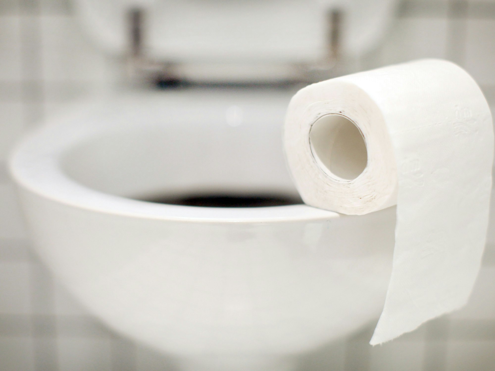 Eine Rolle Toilettenpapier liegt auf dem Toilettenrand.