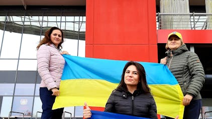 Die Ukrainerinnen (v.l.) Bilozin Liubov, Viktoriia Zhevlova und Nadiia Shepel stehen mit Ukraine-Flaggen vor der Bay-Arena, wo am kommenden Montag, 20. November,das Qualifikationsspiel zur Fußball-Europameisterschaft 2024 zwischen der Ukraine und Italien stattfindet.