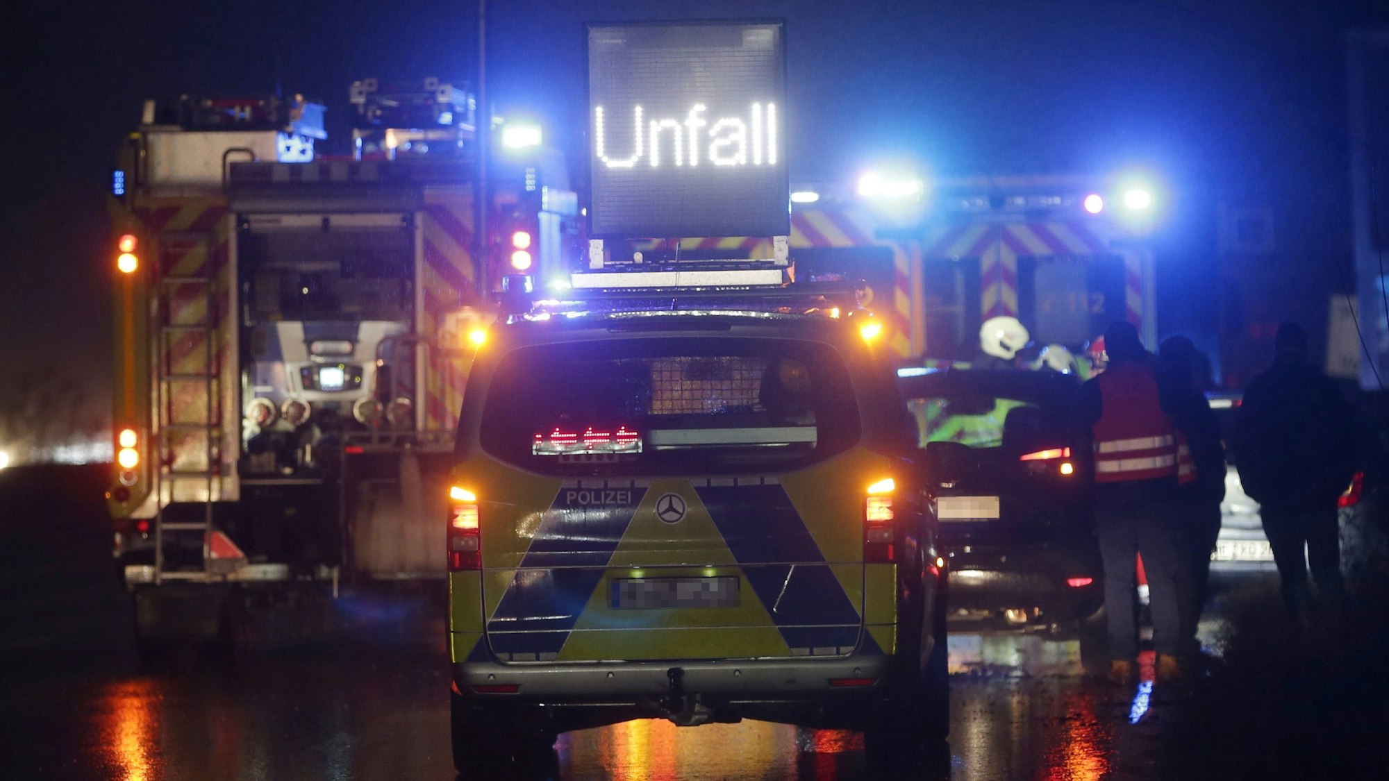 Polizei- und Feuerwehrfahrzeuge sicher mit Blaulicht einen schweren Unfall auf der Autobahn 3. Im Hintergrund sind Rettungskräfte in Warnwesten zu sehen. (Symbolbild)
