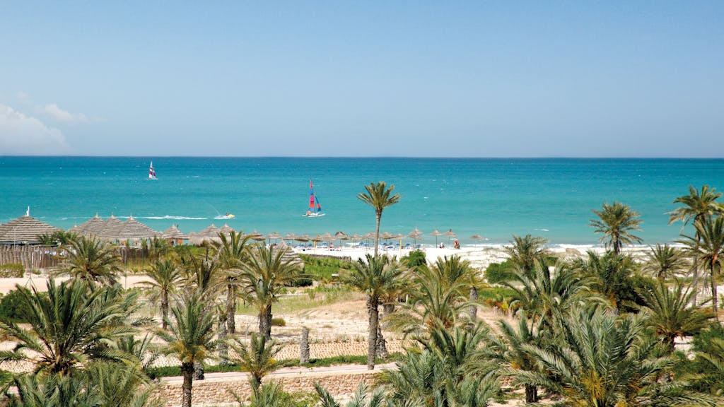 Das Foto zeigt einen Strand mit Palmen und türkisblauem Meer auf der Insel Djerba in Tunesien, aufgenommen im März 2016.