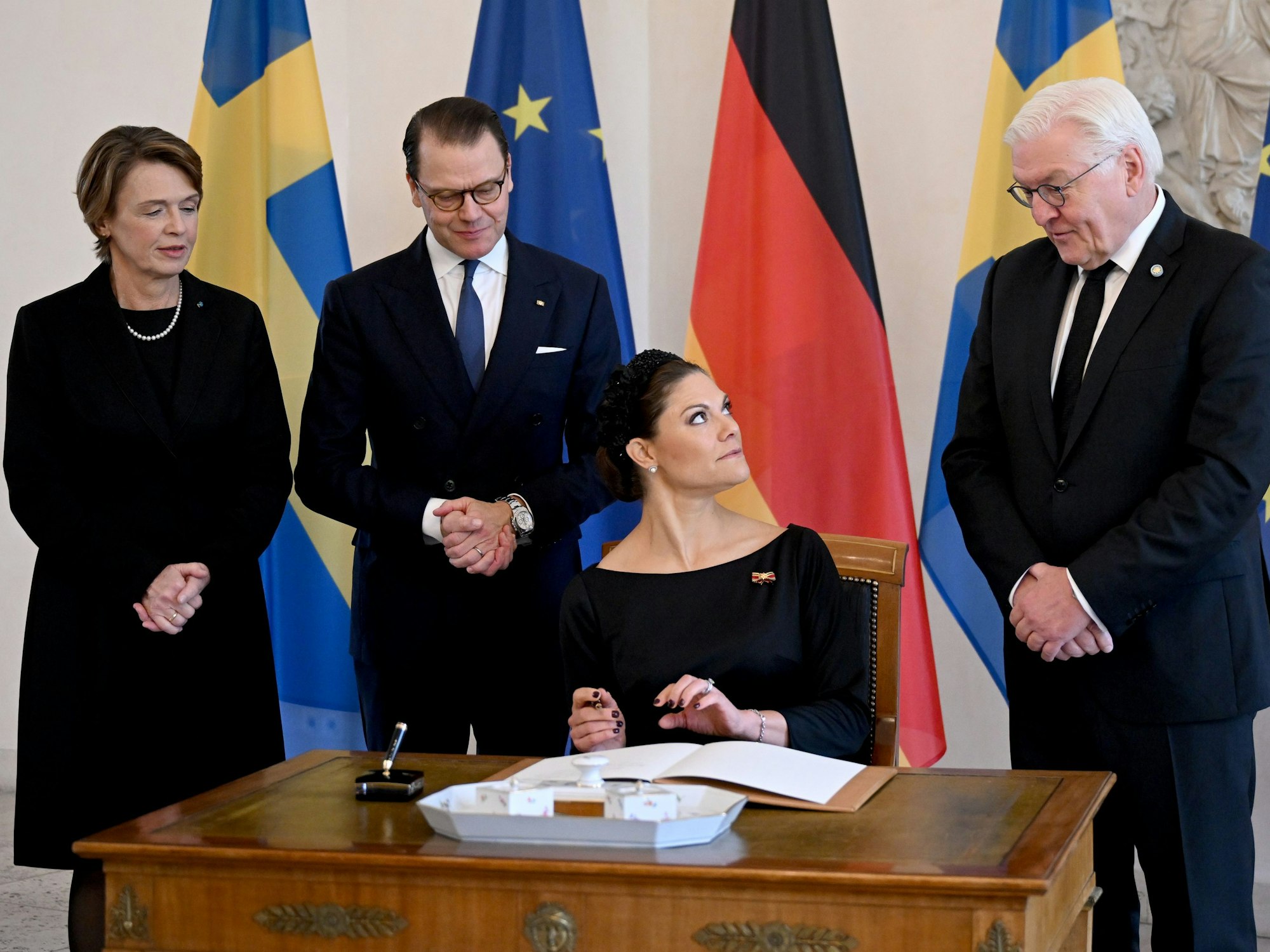 Die schwedische Kronprinzessin Victoria (2.v.r.) und ihr Ehemann Prinz Daniel (2.v.l.) tragen sich in das Gästebuch im Schloss Bellevue ein, während Bundespräsident Frank-Walter Steinmeier (r) und seine Frau Elke Büdenbender (l) hinter ihnen stehen.