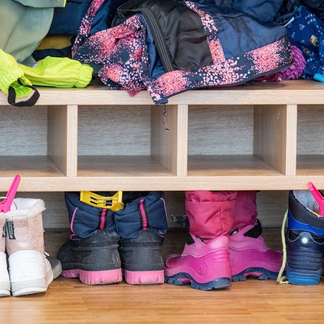 Kinderschuhe stehen nebeneinander auf dem Boden im Garderobenbereich einer Kita.