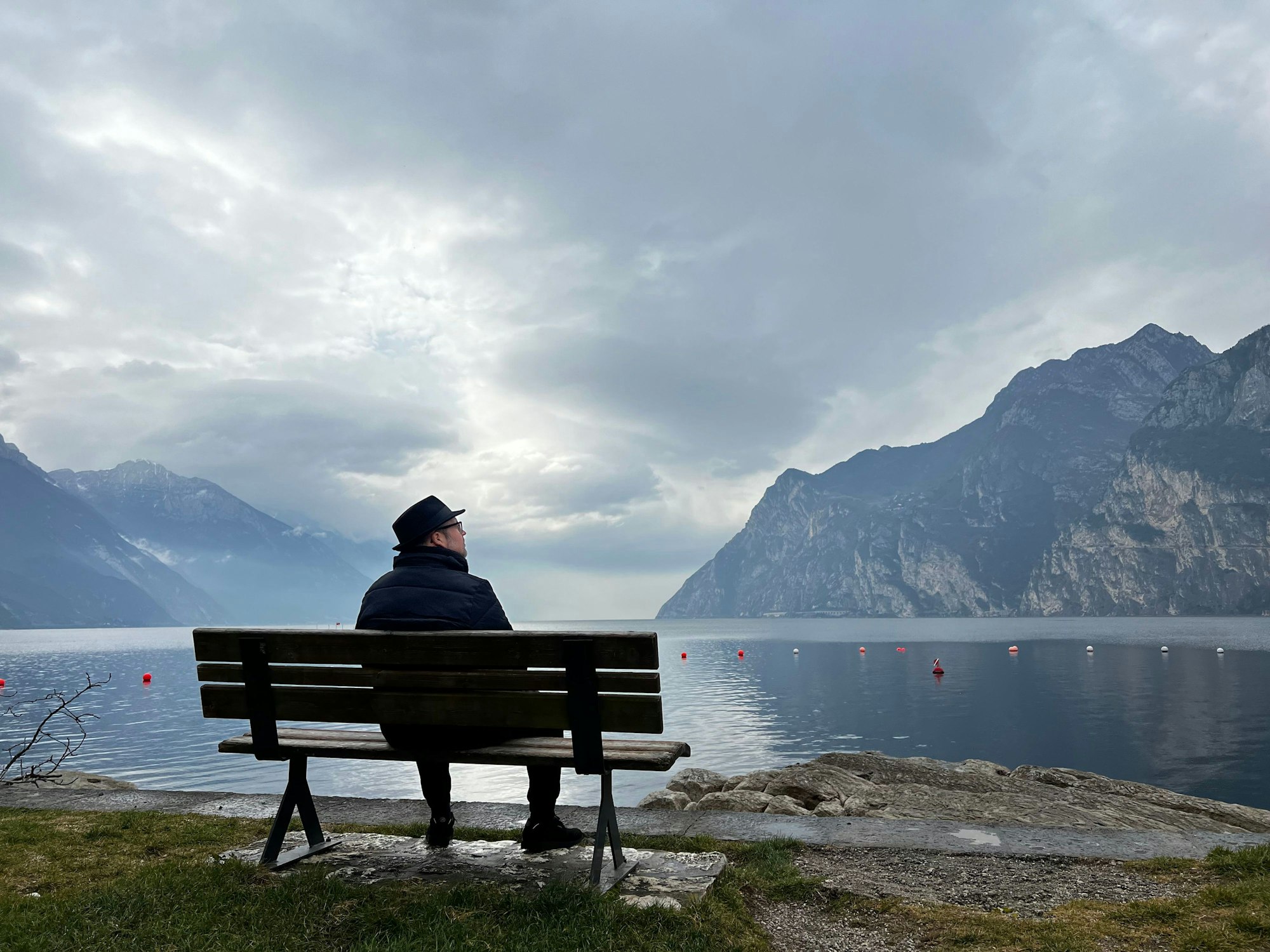Björn Heuser sitzt auf einer Bank am Gardasee.