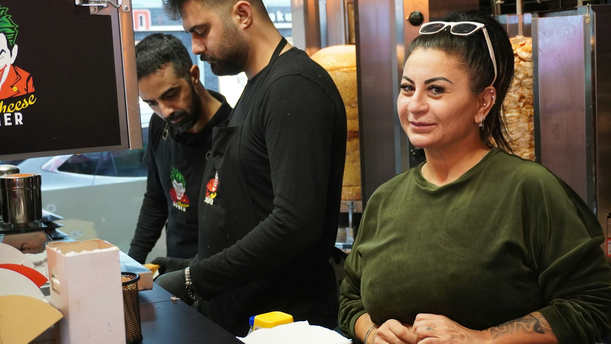 Auf dem Foto ist die Betreiberin des Fast-Food-Lokals, Fatma Ilhan, zu sehen. Angestellte bereiten Döner zu.