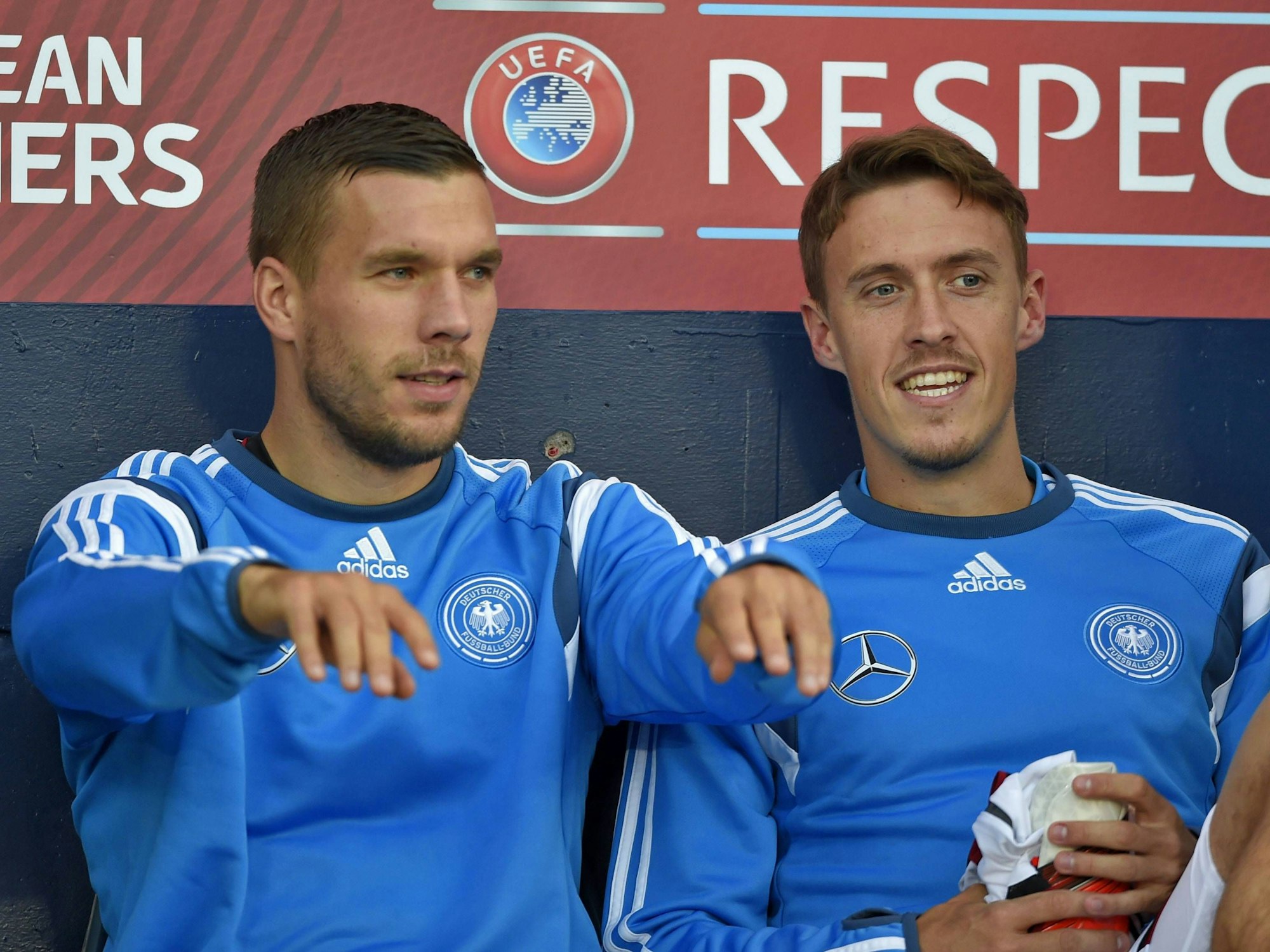 Lukas Podolski und Max Kruse (r.) sitzen bei einem Spiel der deutschen Nationalmannschaft auf der Bank.
