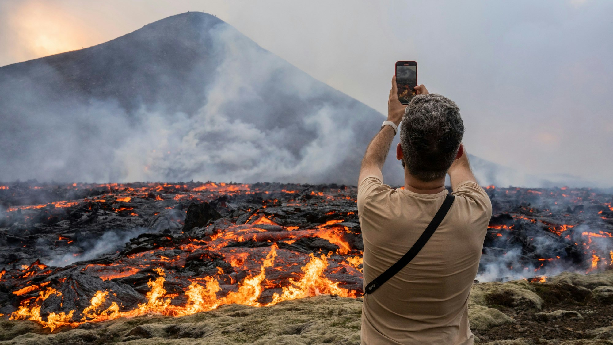 Ein Mann fotografiert, wie Lava aus einer Spalte eines Vulkans in der Nähe des Berges Litli-Hrútur, etwa 30 Kilometer südwestlich von Reykjavik, austritt.