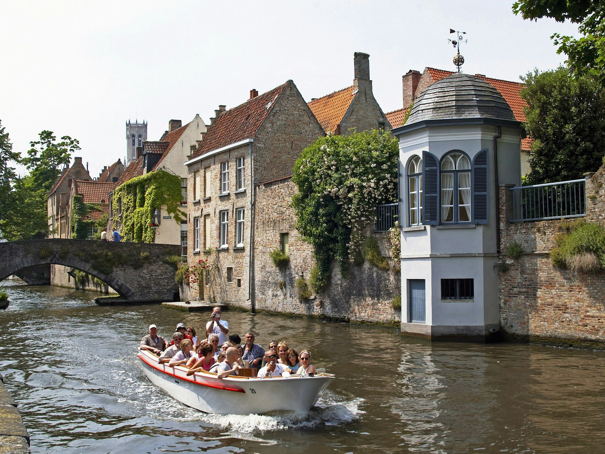 Besucherinnen und Besucher fahren mit einem Boot auf den Grachten von Brügge (Belgien), hier im April 2009.