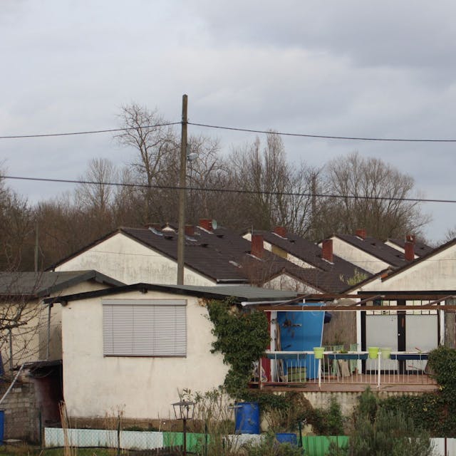 Blick auf verwahrloste Häuser mit ehemals weißen Fassaden.