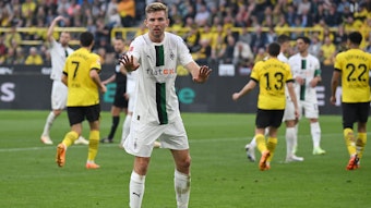 Christoph Kramer will seine Mitspieler nach einem Gegentor beruhigen. Im Hintergrund jubeln Dortmund-Spieler.