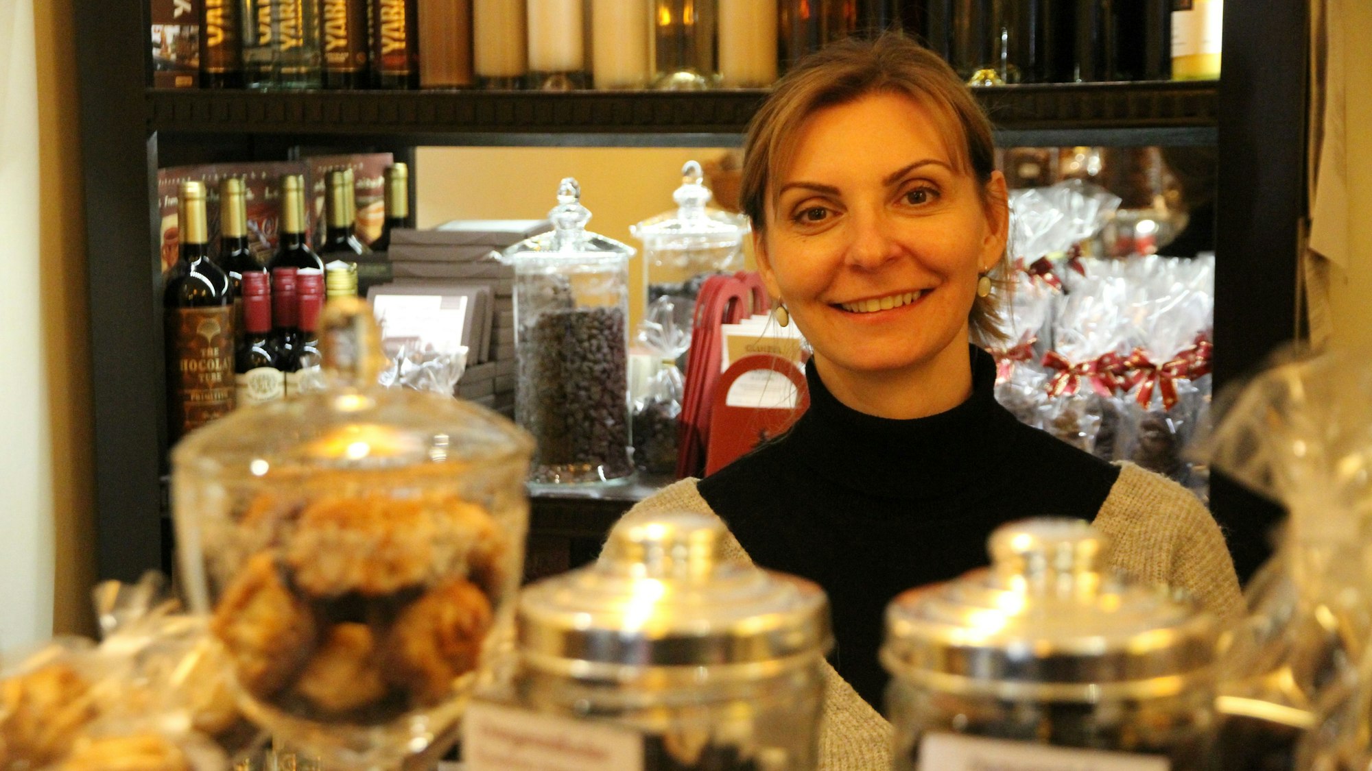 Eine Frau an der Theke ihres Geschäfts mit Schokolade und anderen Süßigkeiten