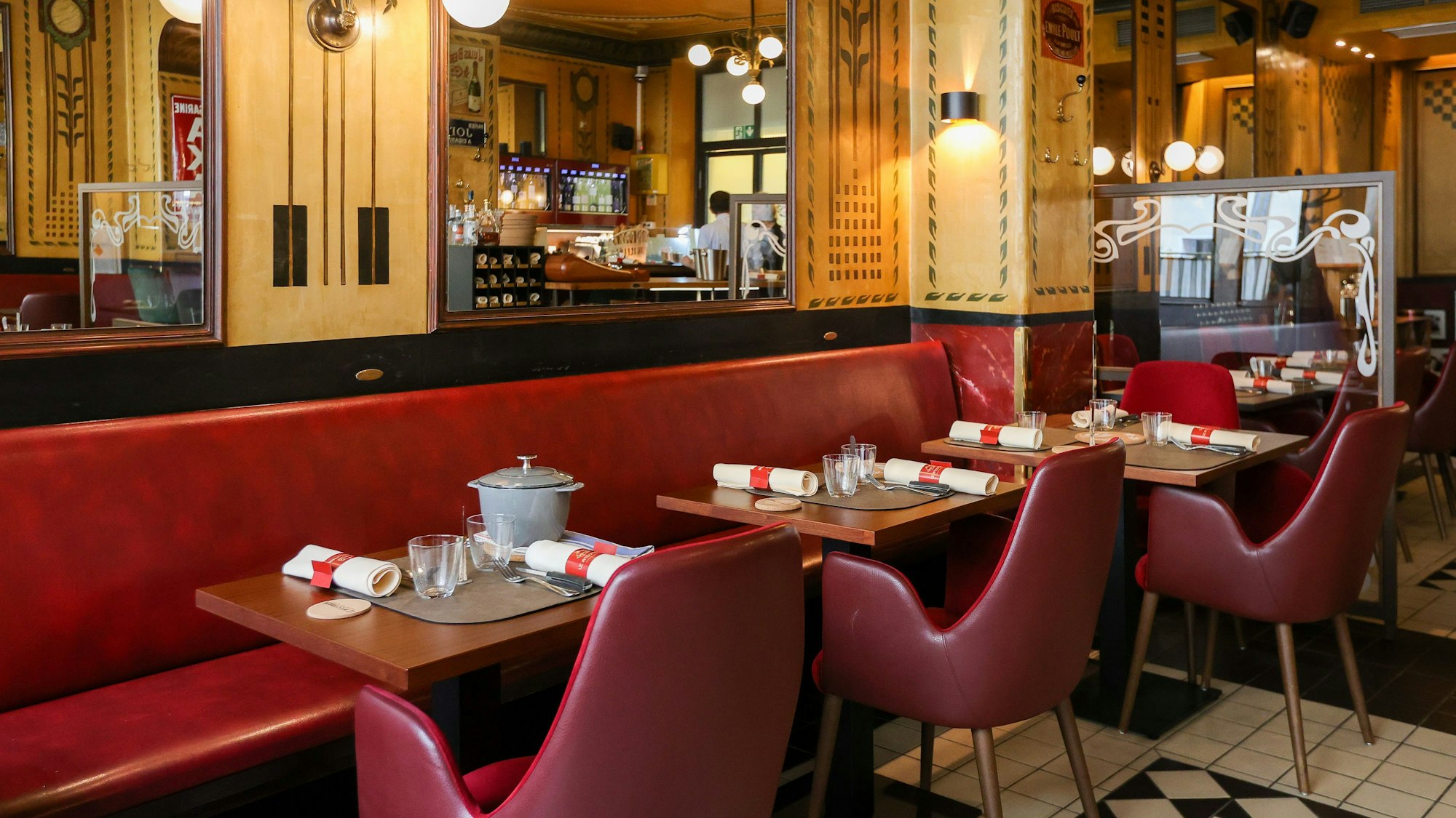 Innenraum des Restaurants, die Tische sind gedeckt und Stühle und Bänke mit rotem Leder bezogen