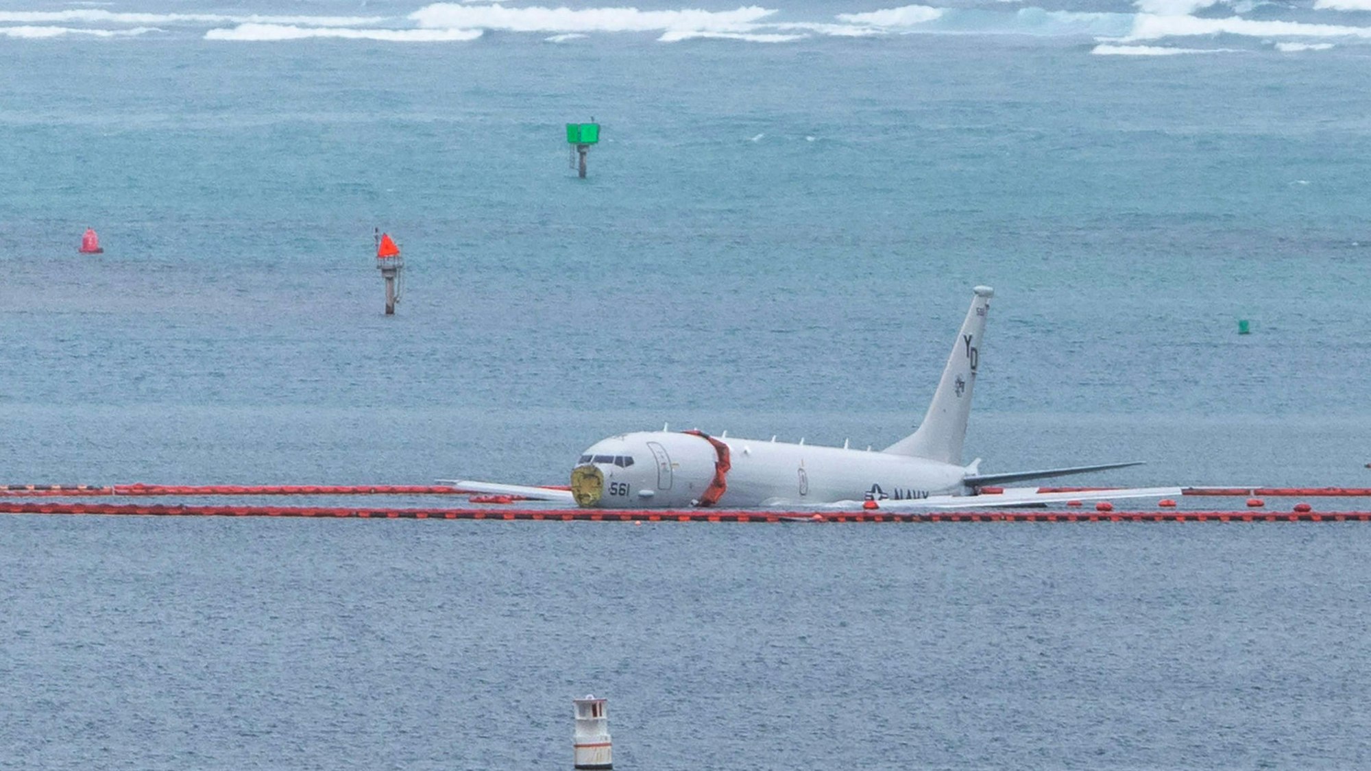 A military aircraft lies in the shallow waters of Kaneohe Bay after skidding off the end of the runway at Marine Corps Hawaii in Kaneohe on November 20, 2023. The aircraft is a Boeing P8 Poseidon, described as a military surveillance and patrol aircraft. Authorities confirmed the nine people on board made it to shore uninjured. The crew was conducting routine training at the time, according to military officials. (Photo by Eugene Tanner / AFP)