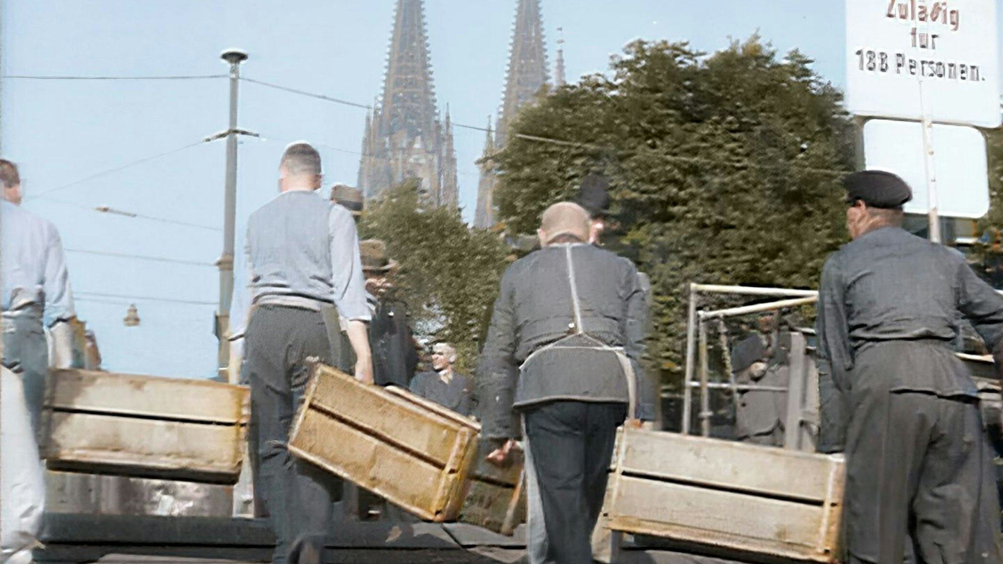 Vier Männer tragen drei Holzkisten in Richtung Rom