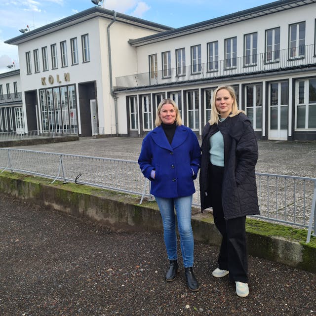 Zwei Frauen stehen vor der historischen Halle des Flughafens Butzweiler Hof.