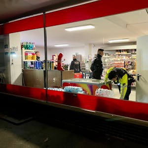 Mitarbeitende von Polizei und Ordnungsamt durchsuchen einen Kiosk in Rheindorf.