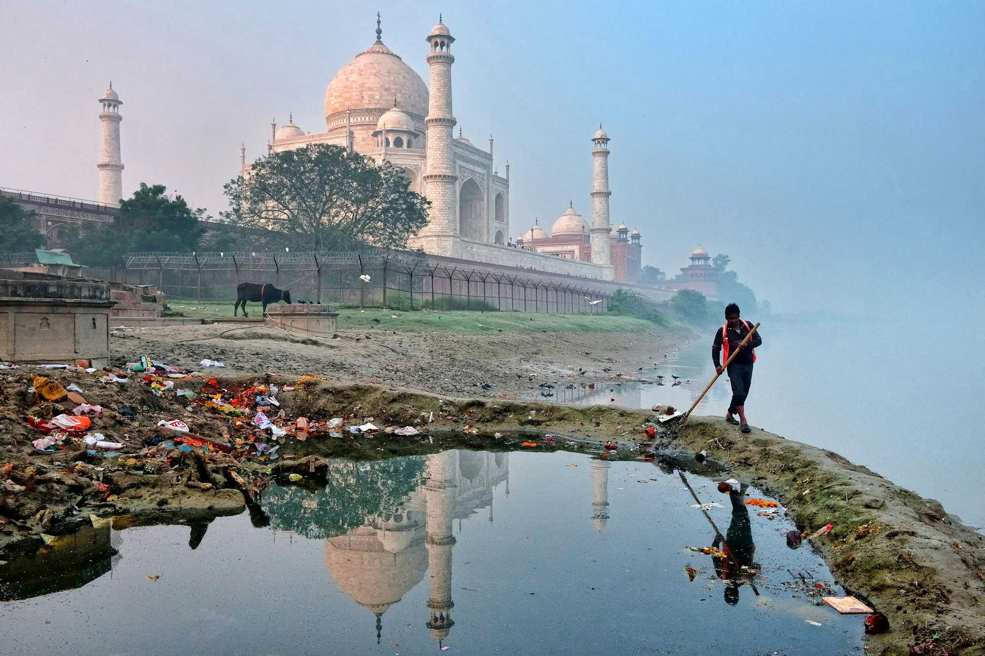 Ein Arbeiter säubert in aller Stille die Umgebung hinter dem Taj Mahal, wo sich einige der örtlichen Abfalldeponien befinden. Diese Szene steht im krassen Gegensatz zu den Ressourcen, die für die Erhaltung und Renovierung des Taj Mahal eingesetzt werden.