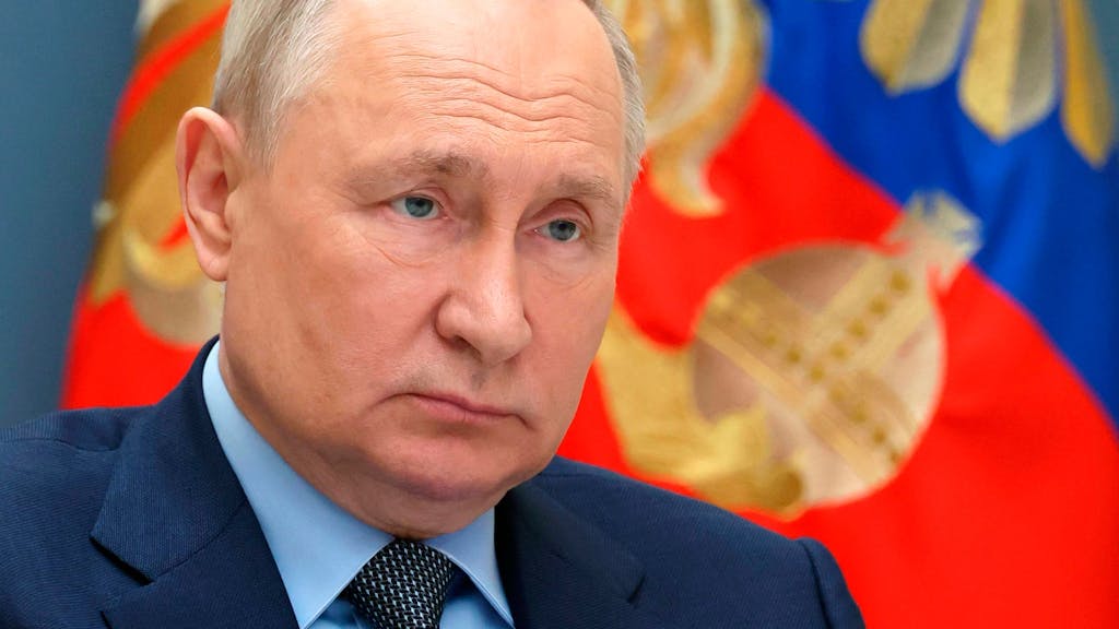Wladimir Putin mit einer russischen Flagge im Hintergrund.