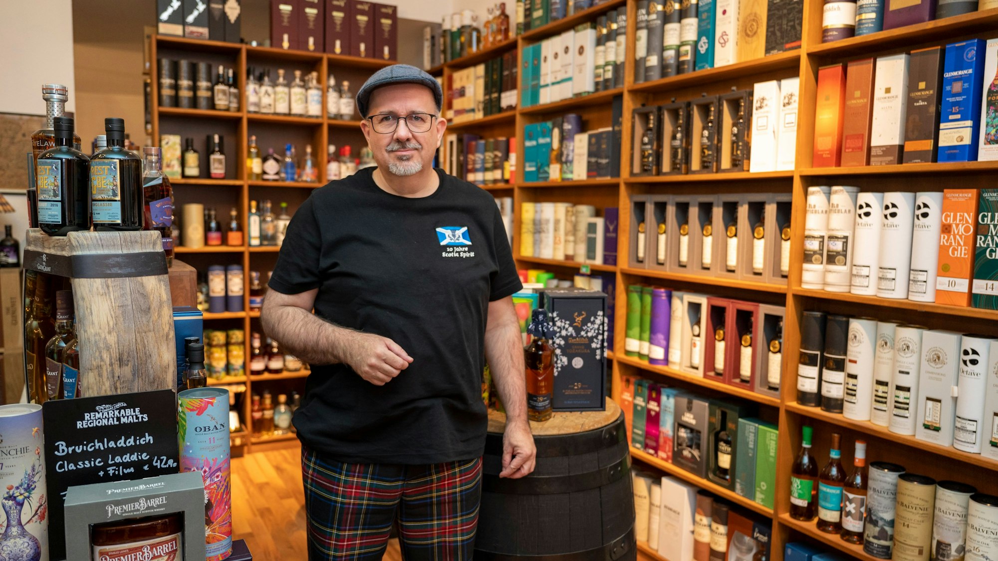 Peter Klas steht in seinem Whisky-Spezialgeschäft vor einem Wandregal mit Flaschen.