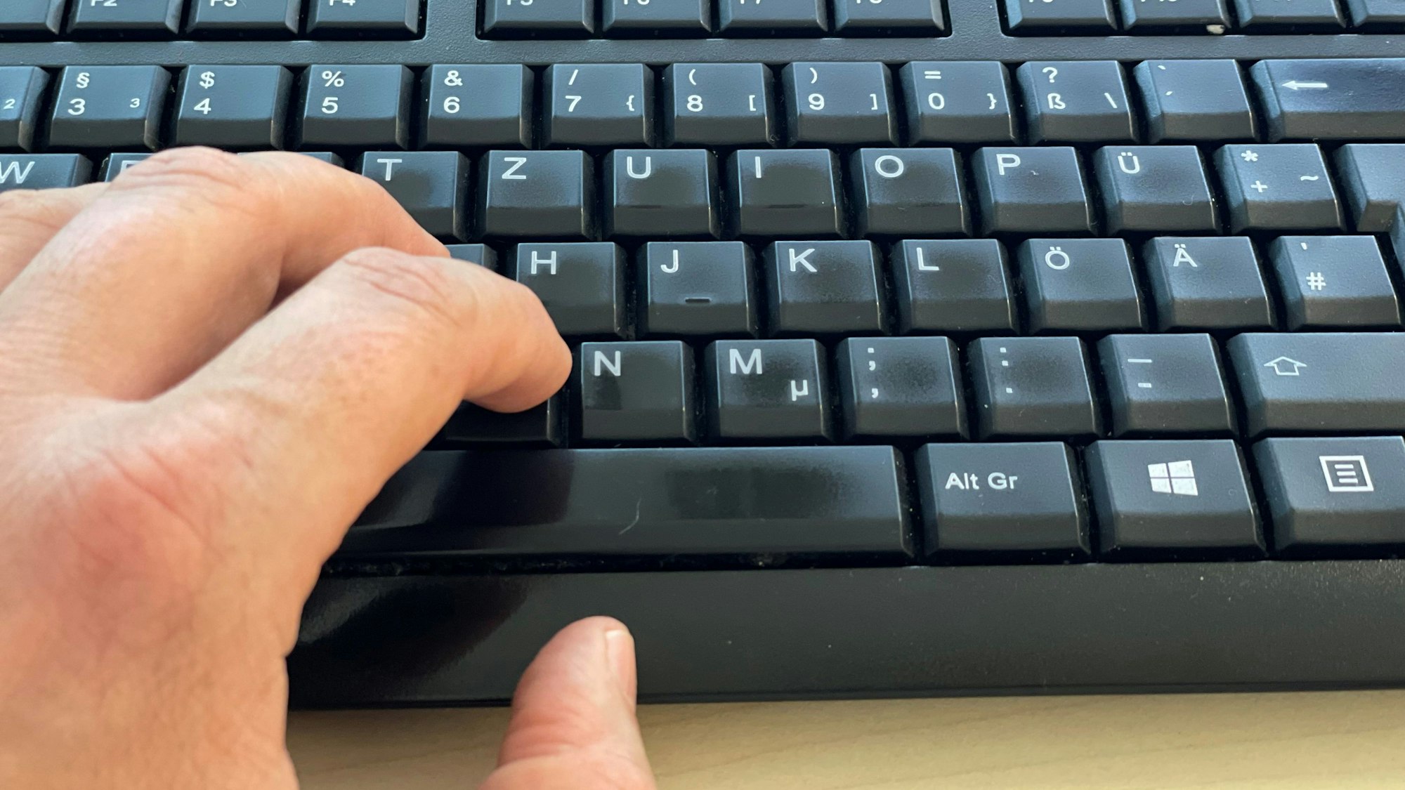 Das Bild zeigt eine Hand auf einer Computer-Tastatur.