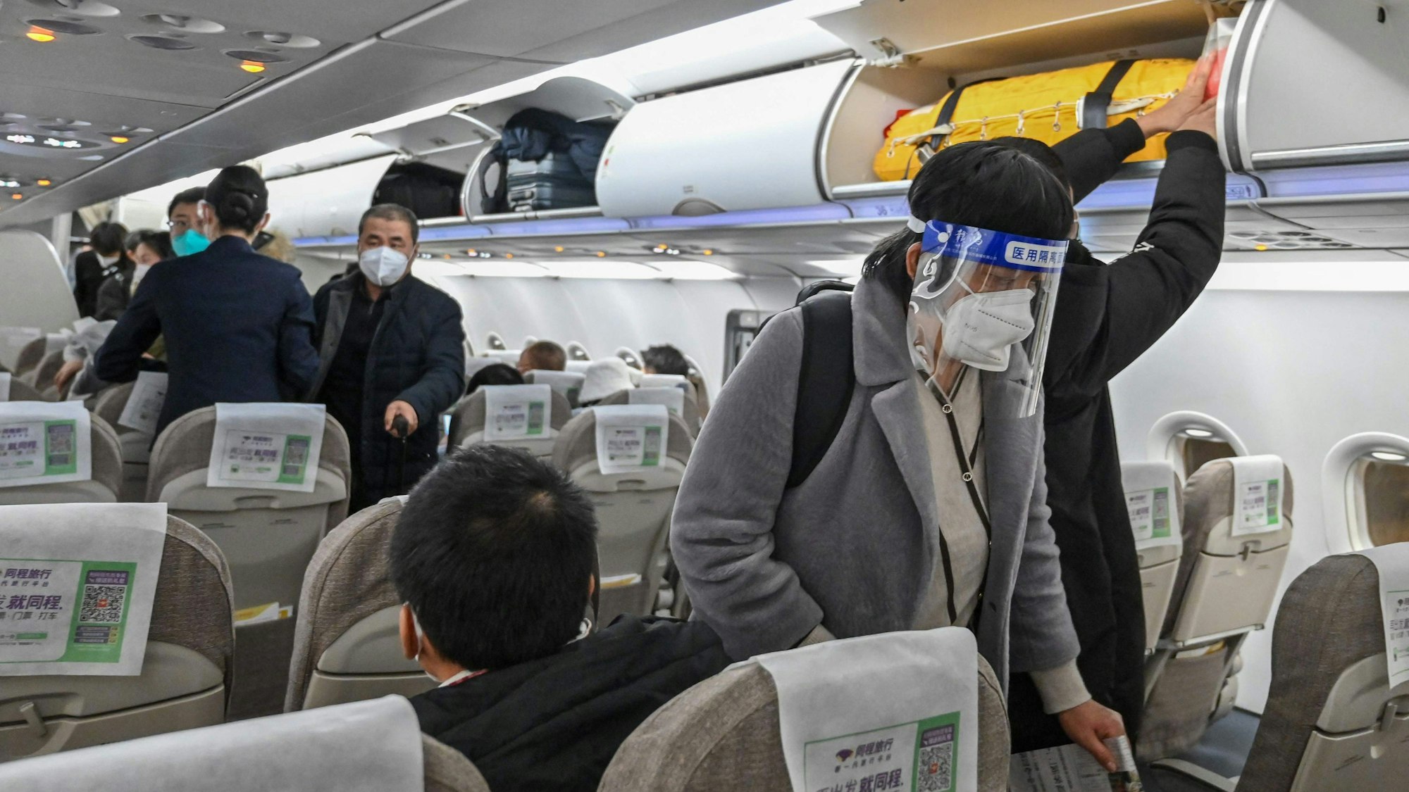 Ein Passagier, der inmitten der Covid-19-Pandemie im Januar 2023 Gesichtsschutz und eine Maske trägt, besteigt einen Inlandsflug am internationalen Flughafen in Shanghai.