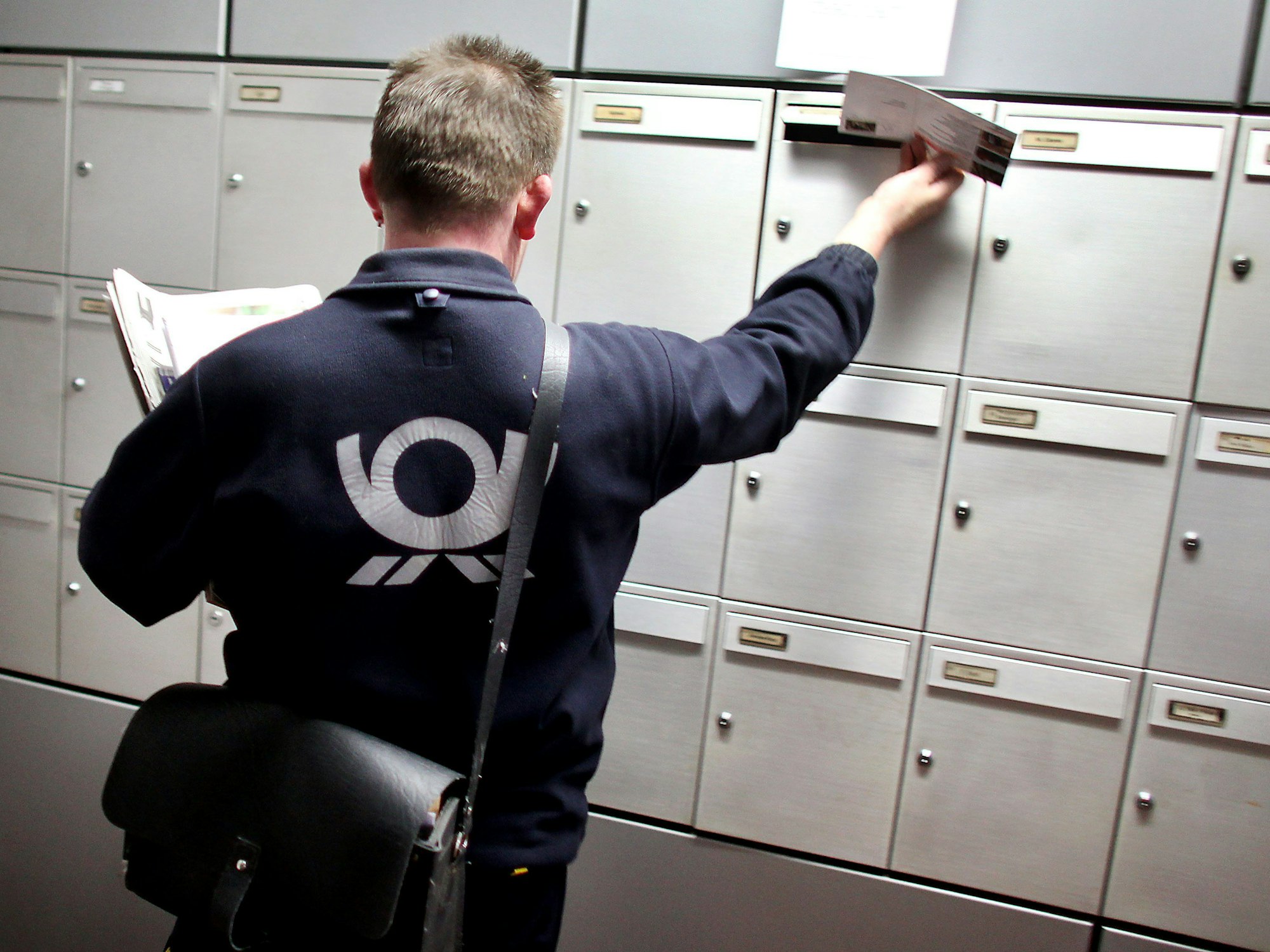 Ein Briefträger der Deutschen Post trägt Briefe aus.