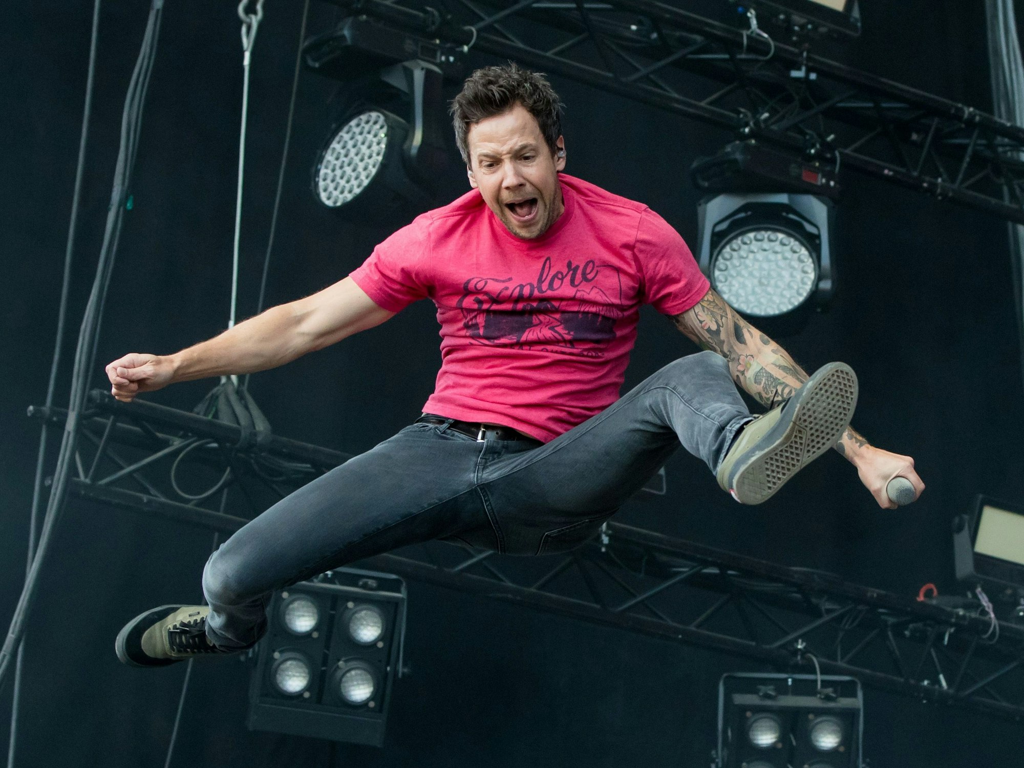 Der Sänger der kanadischen Rockband Simple Plan, Pierre Bouvier, springt in die Luft und spreizt die Beine.