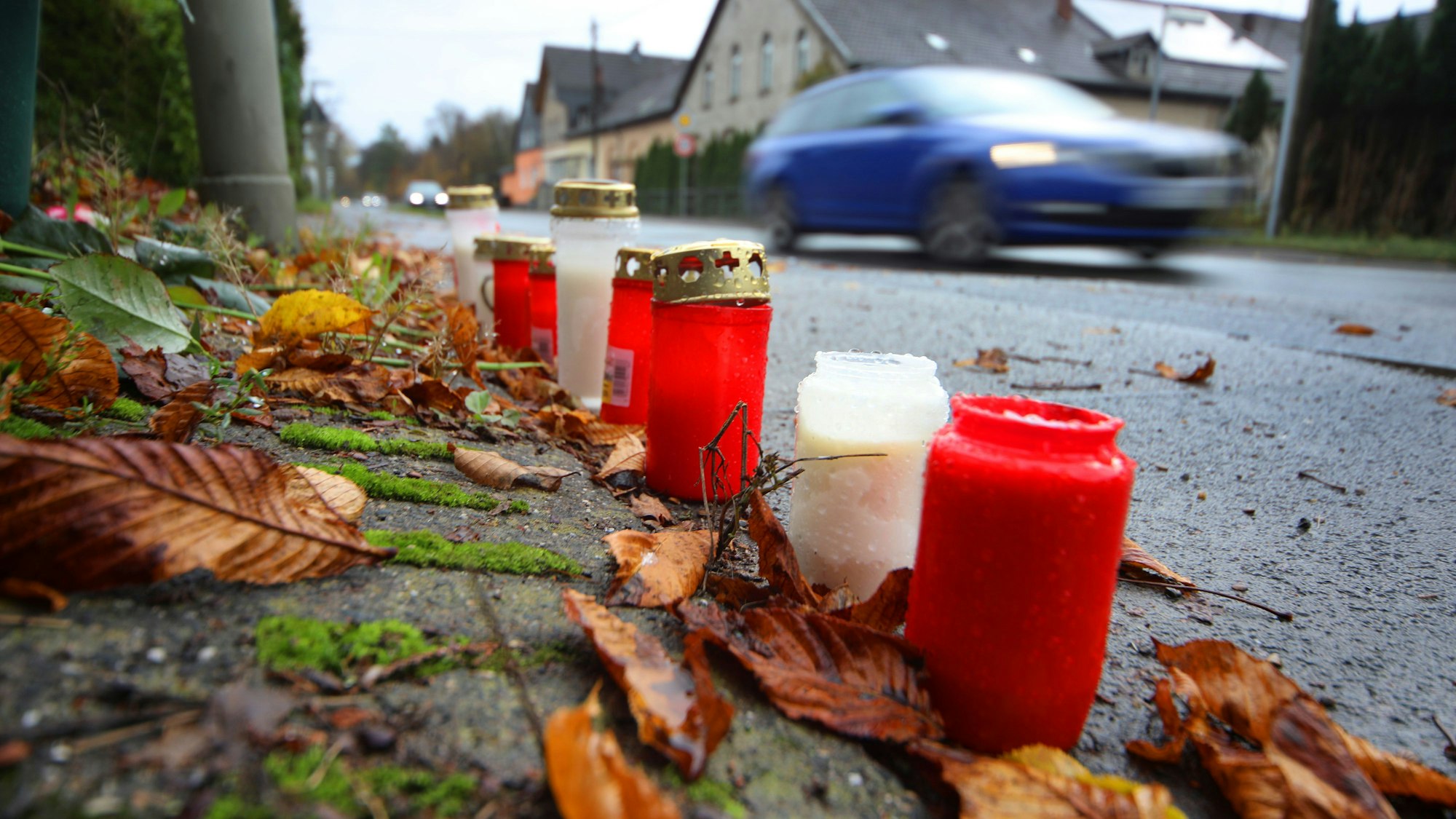 Blumen und Kerzen liegen an der Stelle, an der sich an der Lindlarer Straße in Overath der tödliche Unfall ereignete.