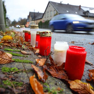Blumen und Kerzen liegen an der Stelle, an der sich an der Lindlarer Straße in Overath der tödliche Unfall ereignete.