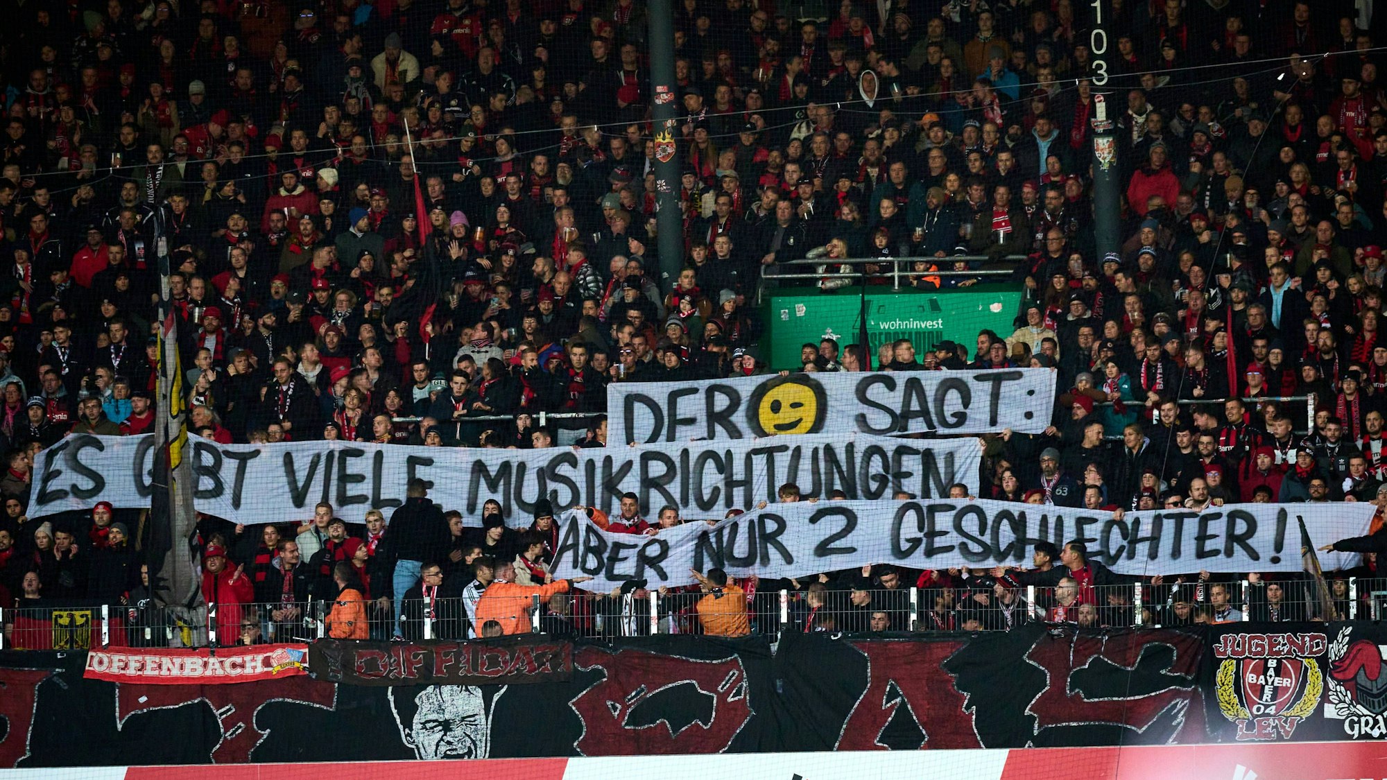 Fans von Bayer Leverkusen halten ein queerfeindliches Plakat hoch