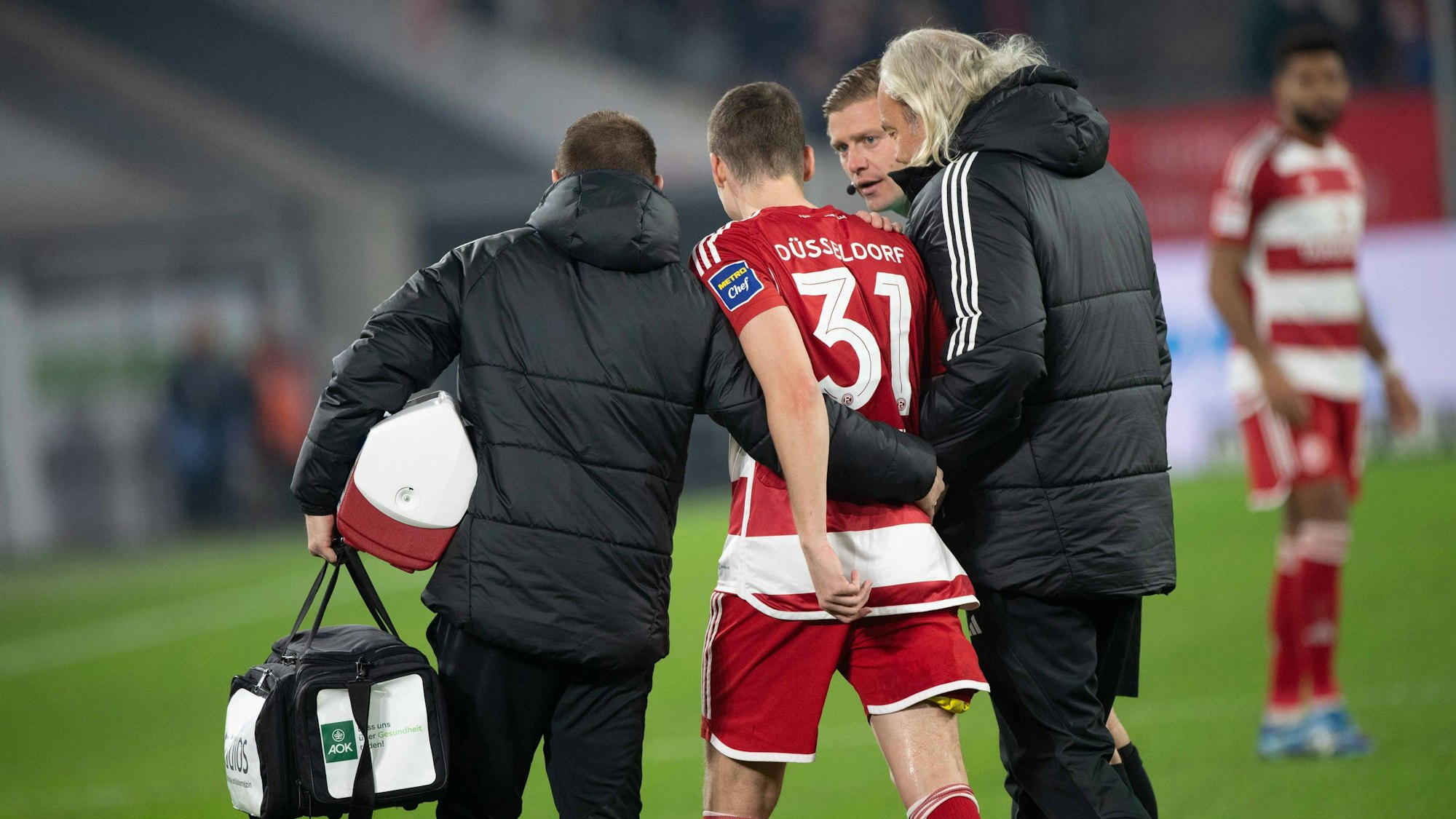 Fortuna Düsseldorfs Marcel Sobottka wird bei seiner Auswechslung im Spiel gegen den FC Schalke 04 von Team-Arzt Ulf Blecker gestützt.