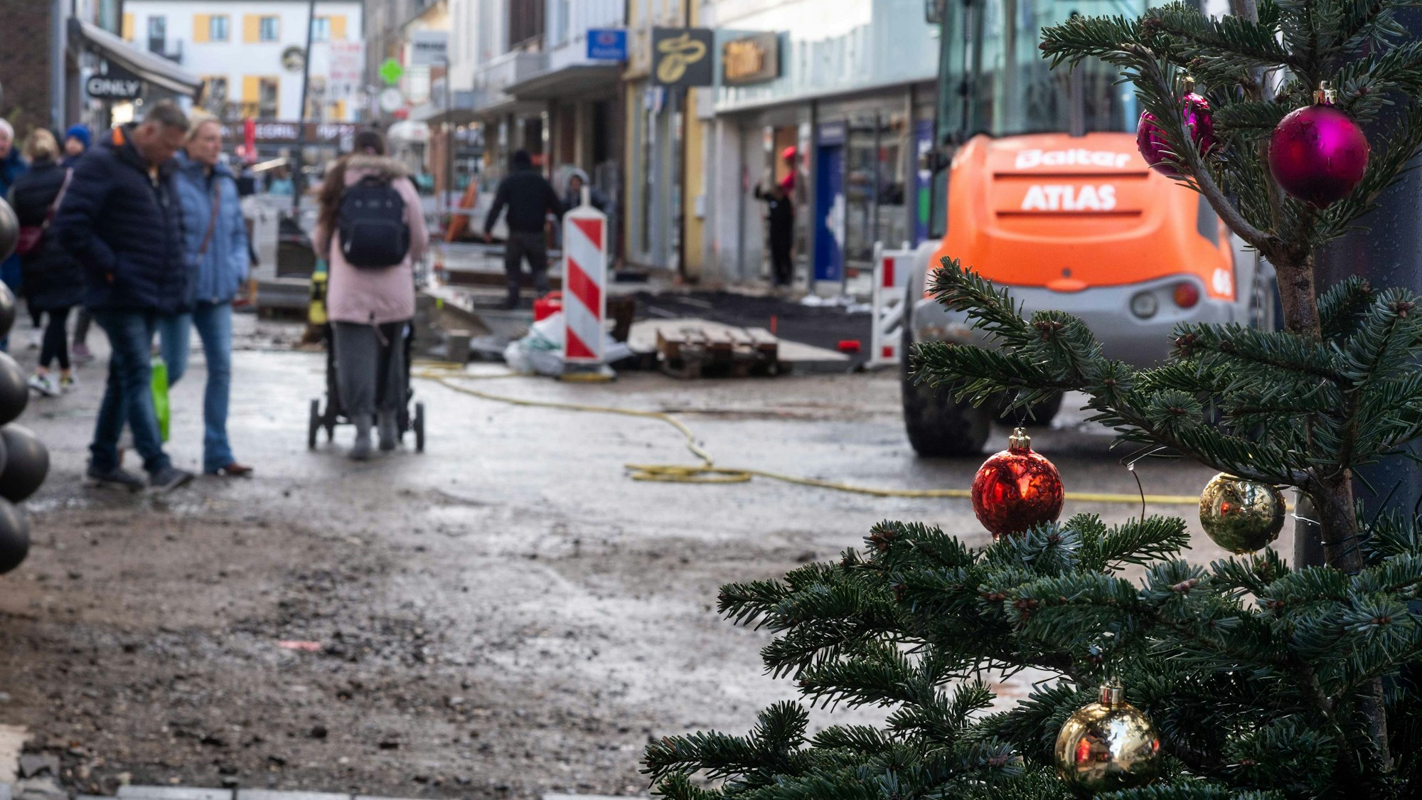 Das Bild zeigt die Euskirchener Fußgängerzone. Am rechten Bildrand ist ein Weihnachtsbaum zu sehen, im Hintergrund die Baustelle an der Neustraße.