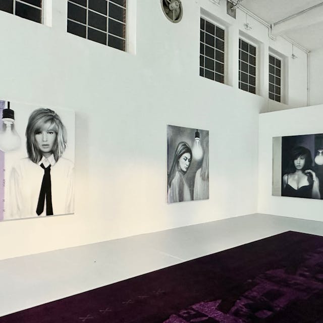 Großformatige Bilder von Frauen hängen an einer weißen Wand.
