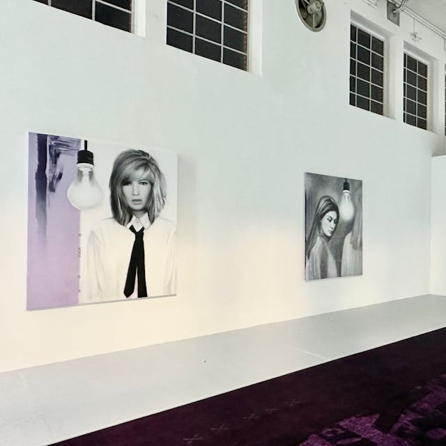 Großformatige Bilder von Frauen hängen an einer weißen Wand.