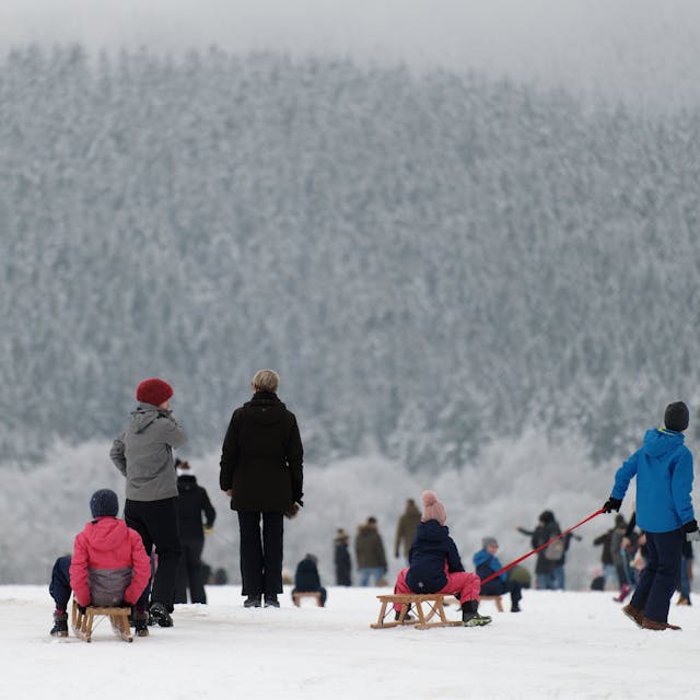 Spaziergänger und Rodelfreunde genießen das Winterwetter im Skigebiet „Weißer Stein“ in der Eifel.