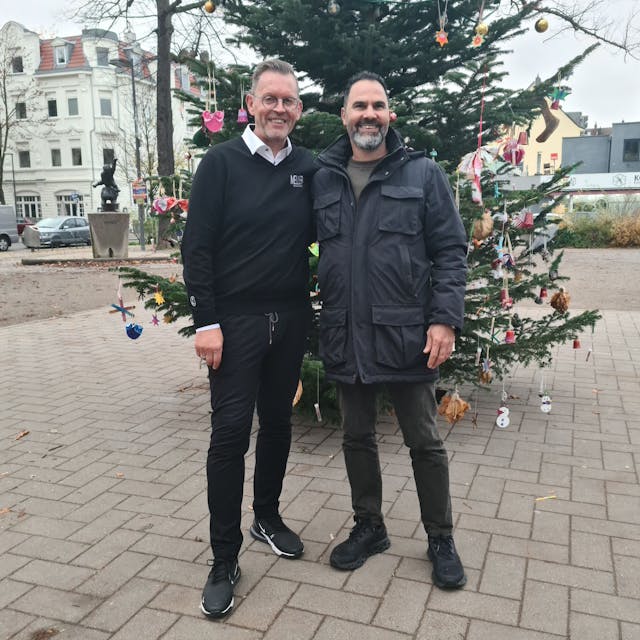 Zwei Leute vor einem Weihnachtsbaum.