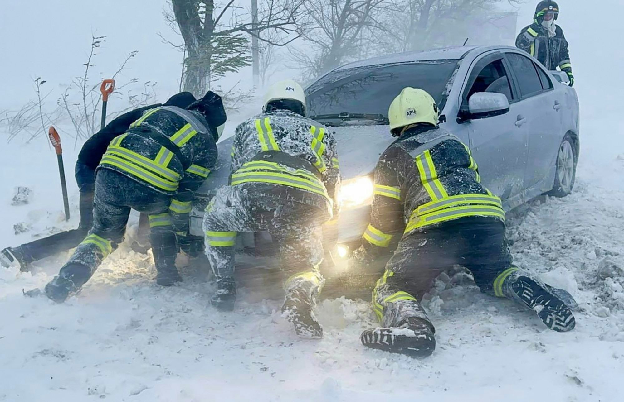 Auf diesem vom ukrainischen Rettungsdienst zur Verfügung gestellten Bild versuchen ukrainische Rettungskräfte ein im Schnee steckengebliebenes Auto auf der Autobahn in der Region Odessa zu schieben.