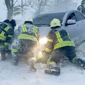 Auf diesem vom ukrainischen Rettungsdienst zur Verfügung gestellten Bild versuchen ukrainische Rettungskräfte ein im Schnee steckengebliebenes Auto auf der Autobahn in der Region Odessa zu schieben.