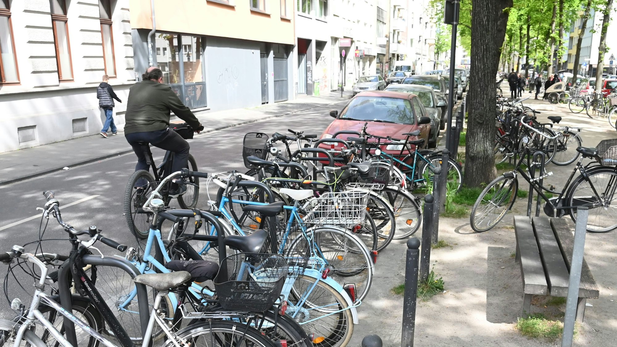 Auf einer Straße in Köln sind dutzende Fahrräder am Straßenrand zu sehen.