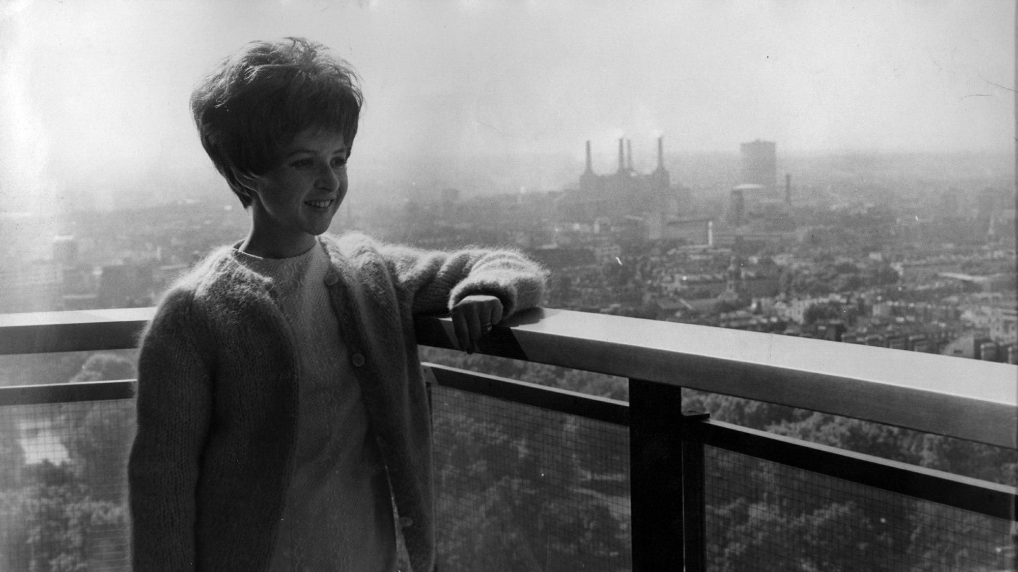 20th August 1964:  American pop star Brenda Lee admires the view from her Hilton Hotel apartment during a trip to London for recording and TV appearances. Battersea power station can be seen in the distance.  (Photo by Kent Gavin/Keystone/Getty Images)
