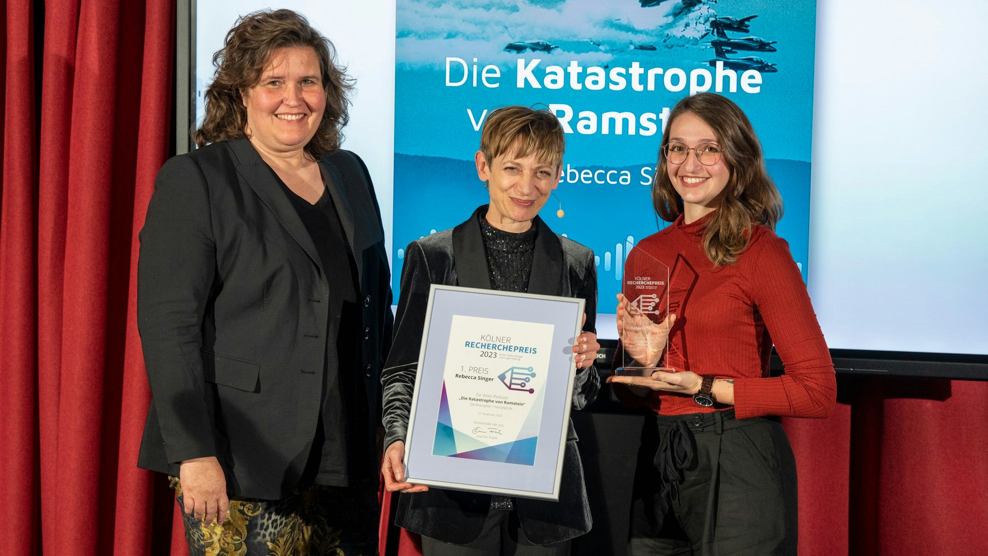 Annette Binninger (Chefredaktion „Sächsische Zeitung“, links) übergab die Preis-Statuette für den 1. Preis an Rebecca Singer (rechts). In der Mitte Moderatorin Katharina Schmalenberg mit Singers Urkunde.